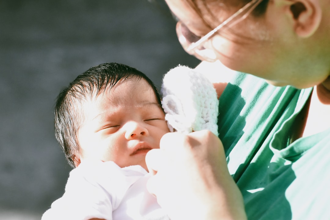 A parent holds a sleeping newborn baby.