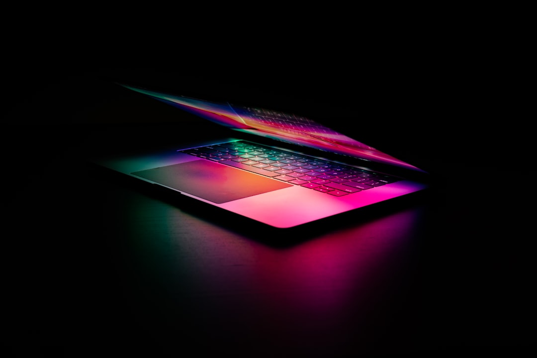 A laptop with a glowing keyboard illuminated by vibrant pink and green light