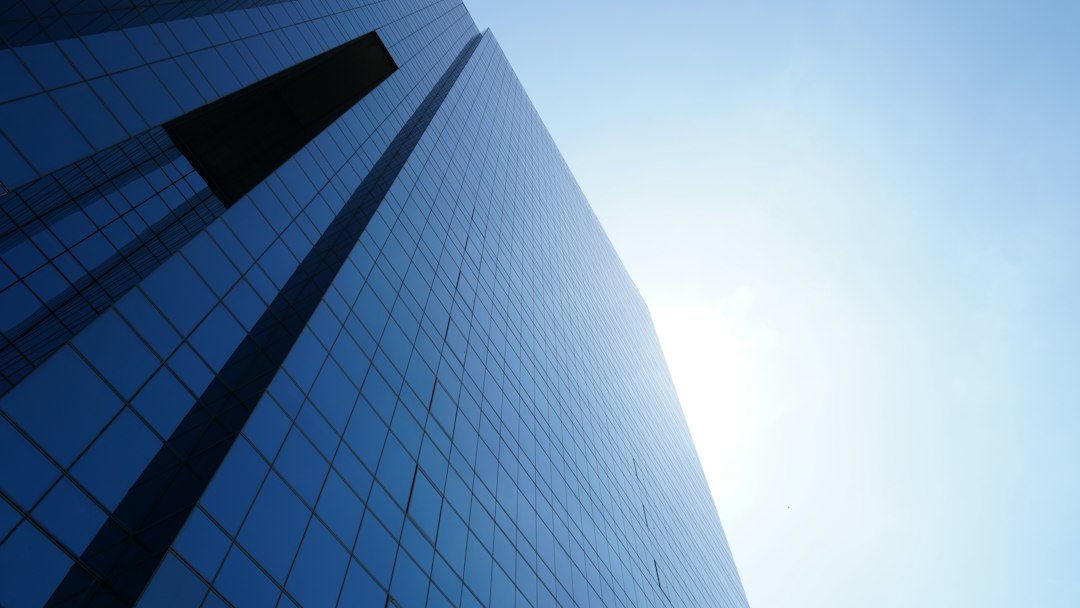 tall blue glass paneled building under clear blue sky
