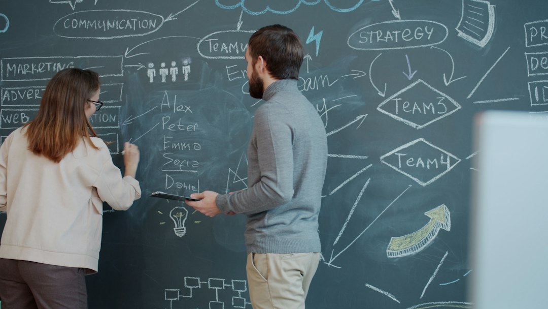 Two people planning on a chalkboard with diagrams