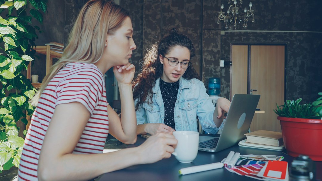 Two women discuss something on a laptop