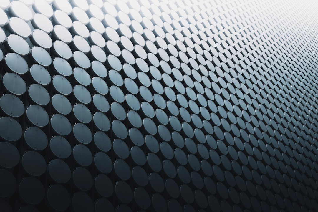 A repeating pattern of circular metallic discs on a dark gradient background